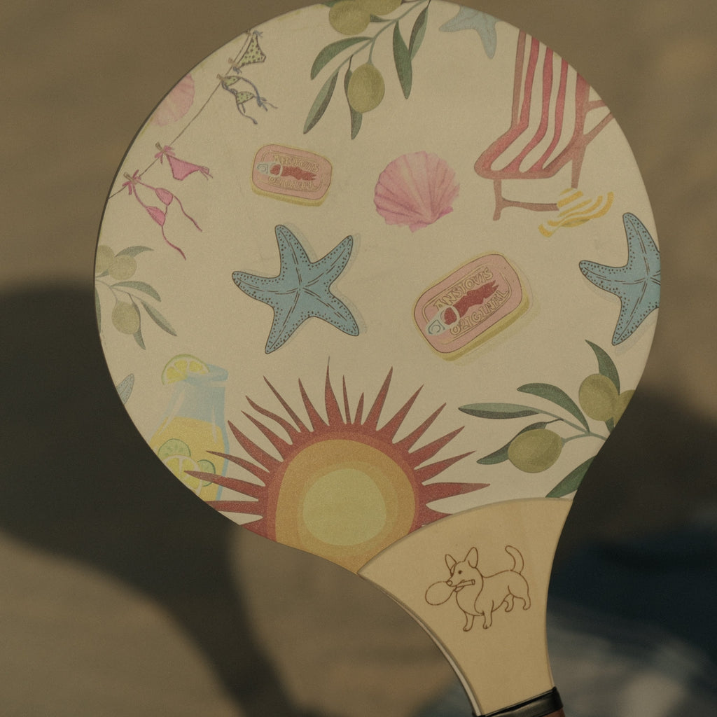 Paddle with beach-themed design featuring stars, sun, and seashells on a beige background.