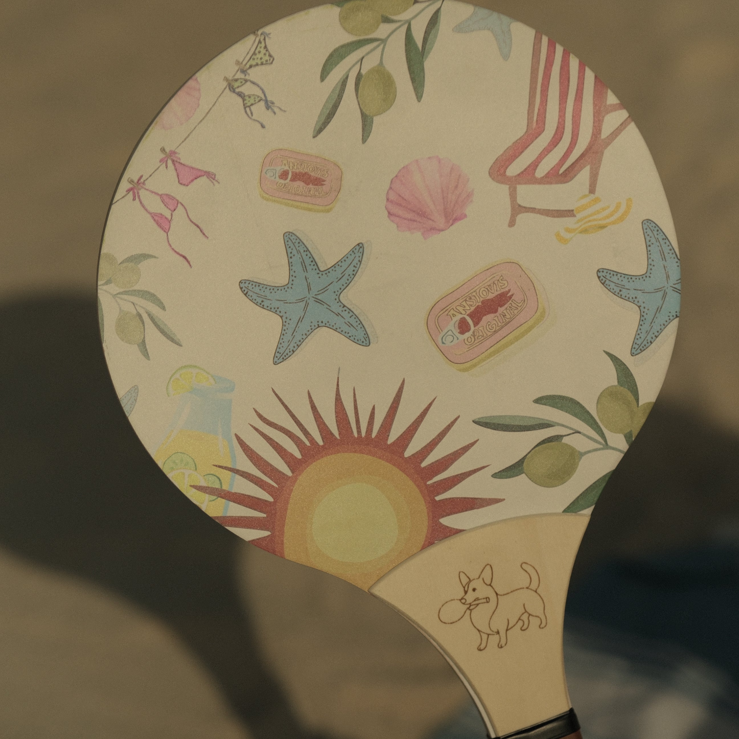 Paddle with beach-themed design featuring stars, sun, and seashells on a beige background.