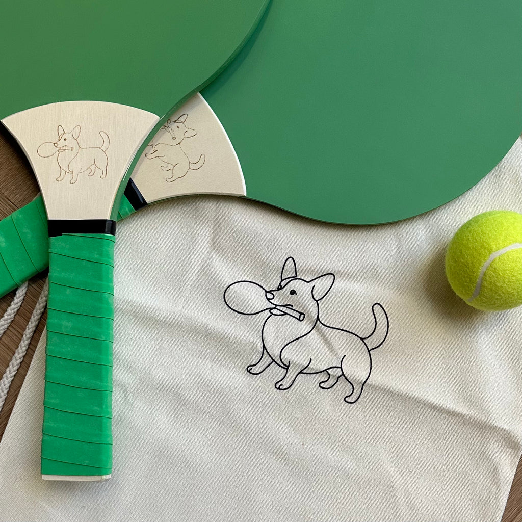 Two green soft pastel wooden paddle tennis rackets with a drawstring bag and ball