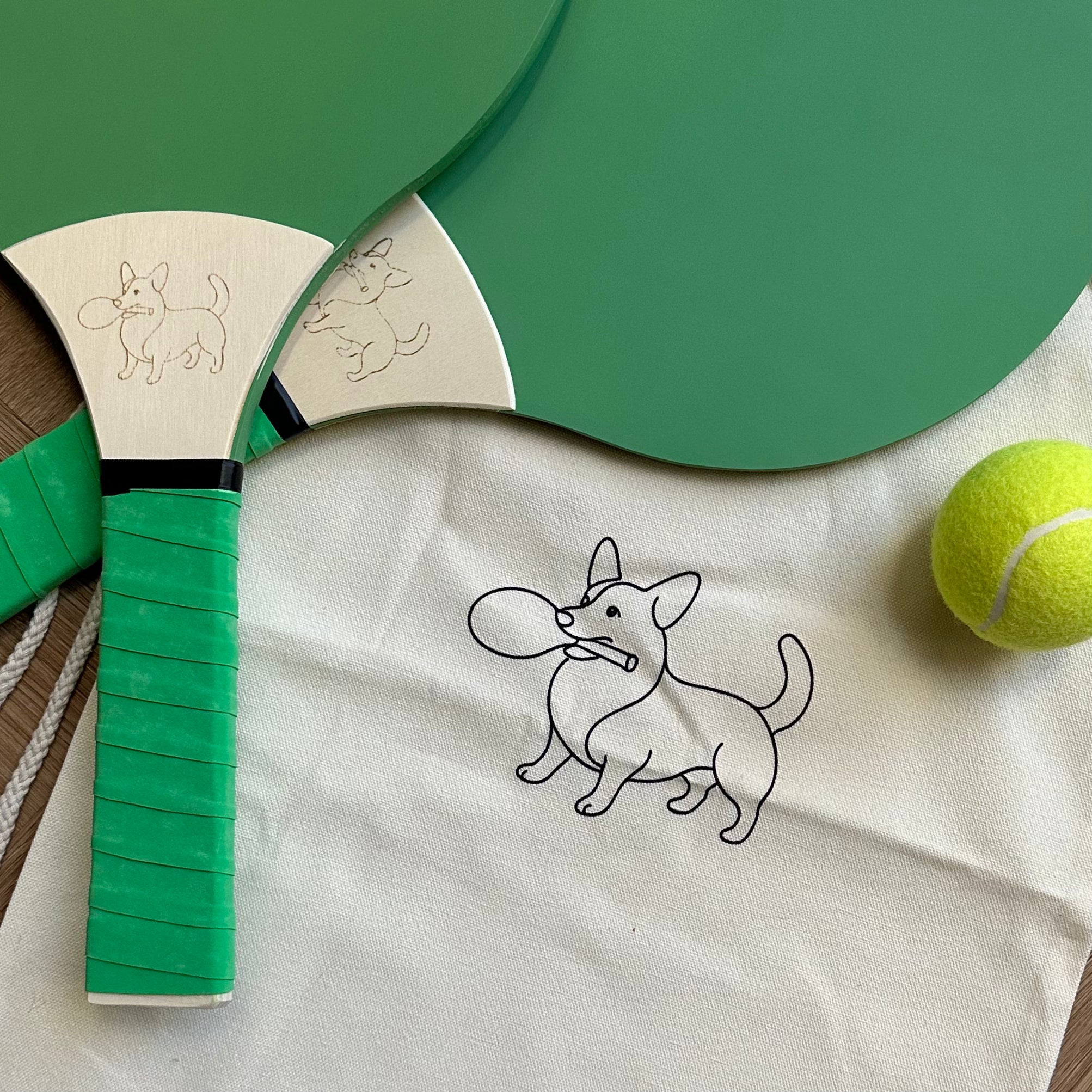 Two green soft pastel wooden paddle tennis rackets with a drawstring bag and ball
