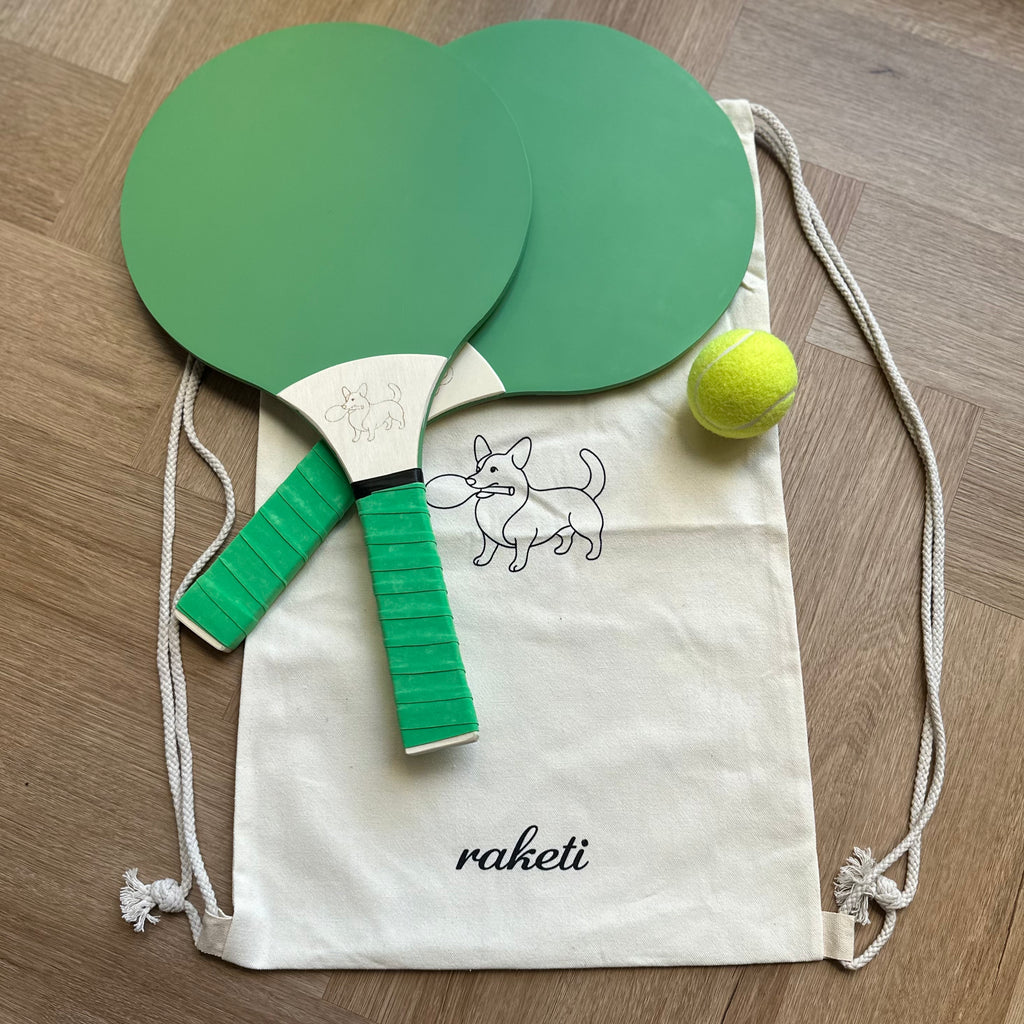 Two green soft pastel wooden paddle tennis rackets with a drawstring bag and ball
