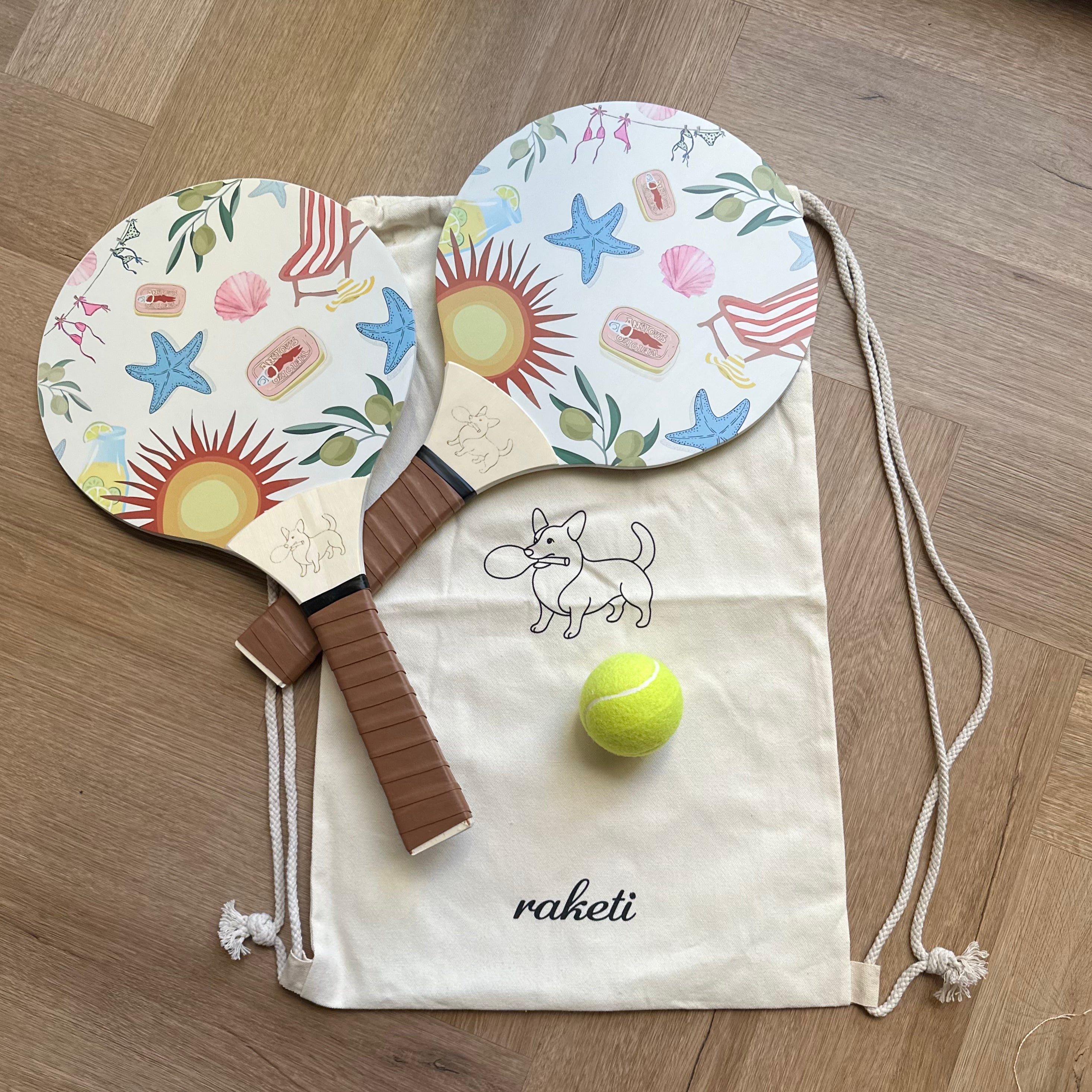Two wooden paddle tennis rackets with summer fun designs with a drawstring bag and ball