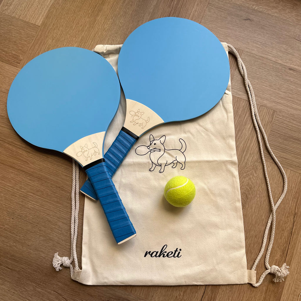 Two wooden paddle tennis rackets soft blue with a drawstring bag and ball